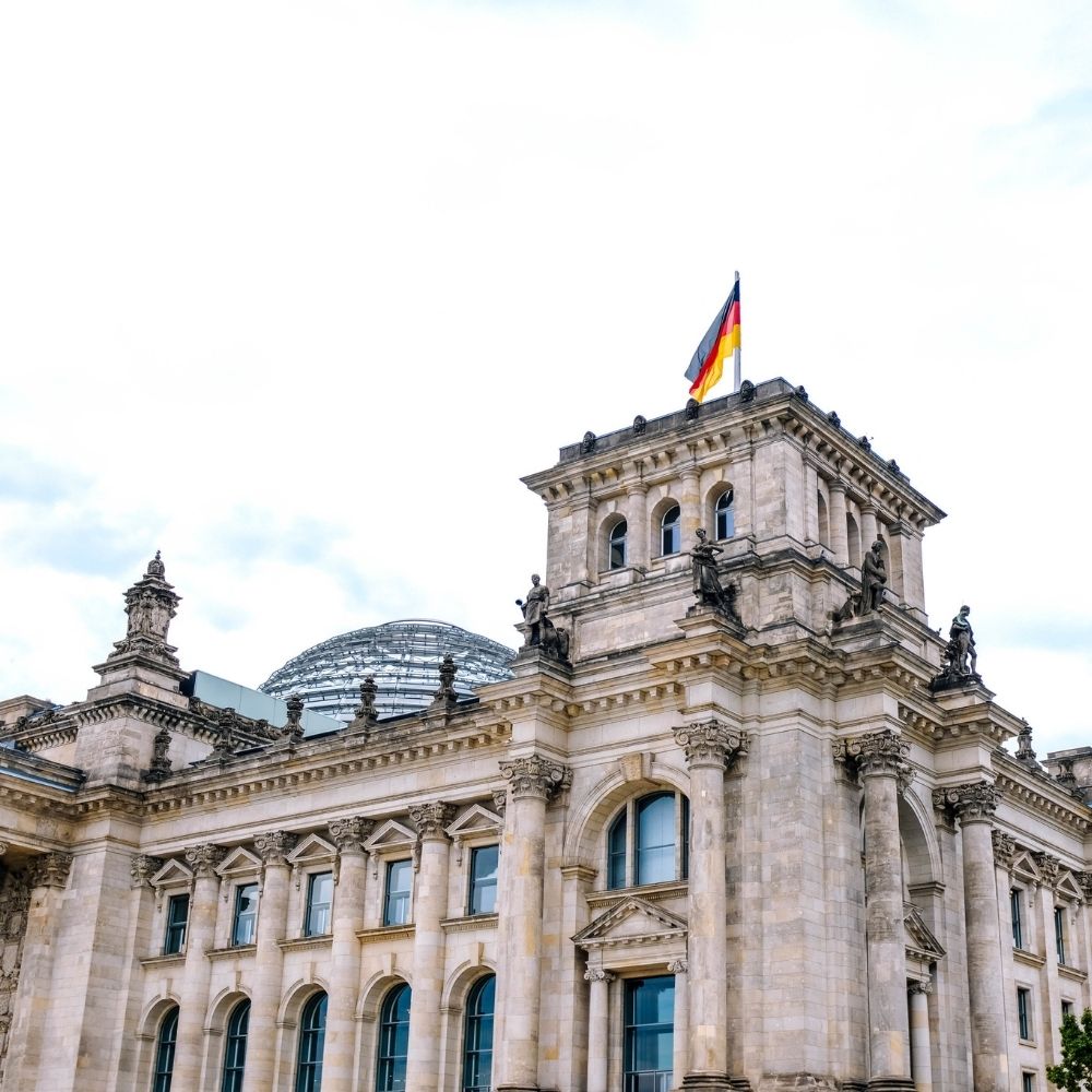 Stock image of the German flag flying atop the Reichstag building in Berlin, capturing the city’s architectural prominence and historical significance—ideal for contextual storytelling or backdrop use in the Berlin collection