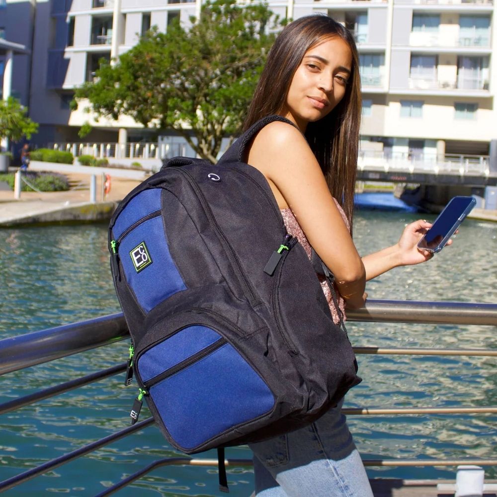 Woman standing near waterfront holding phone with Eco laptop backpack – lifestyle product image 01