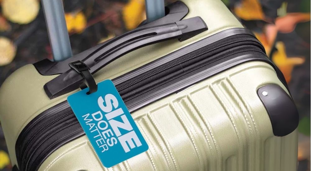 Feature highlight lifestyle image of a luggage tag attached to a suitcase handle, captured mid-journey to emphasize practical utility, travel identity, and minimalist accessory design