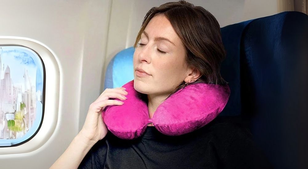 Lifestyle image of a pink Neck Pillow placed beside travel essentials like a map, coffee, and camera gear, evoking a relaxed, on-the-go setup with comfort and style in mind