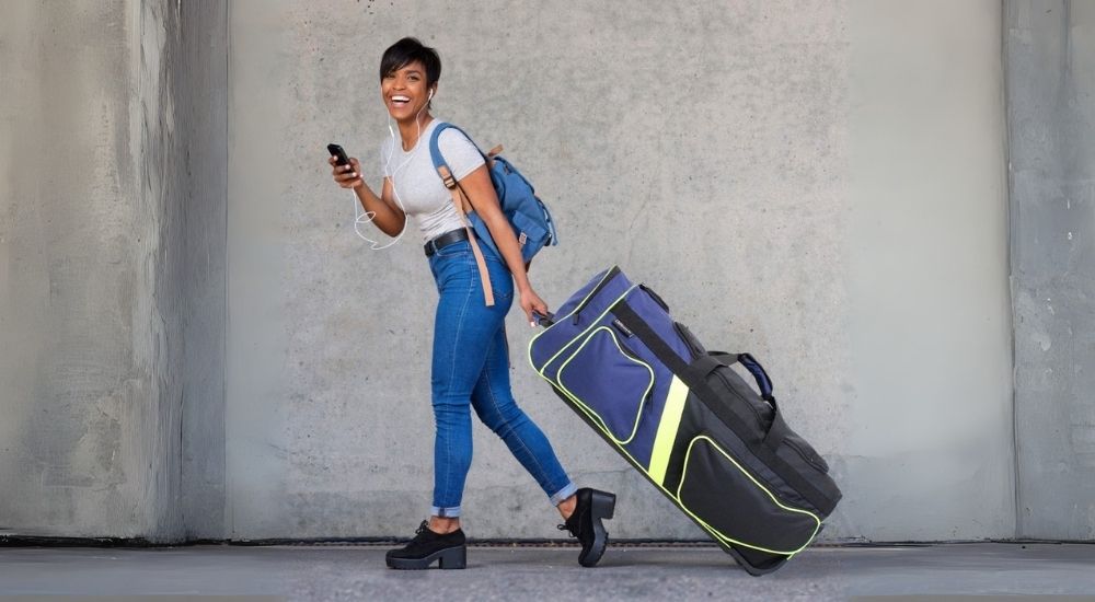 Woman walking with large Eco roller duffel bag in blue and lime – lifestyle product image 01