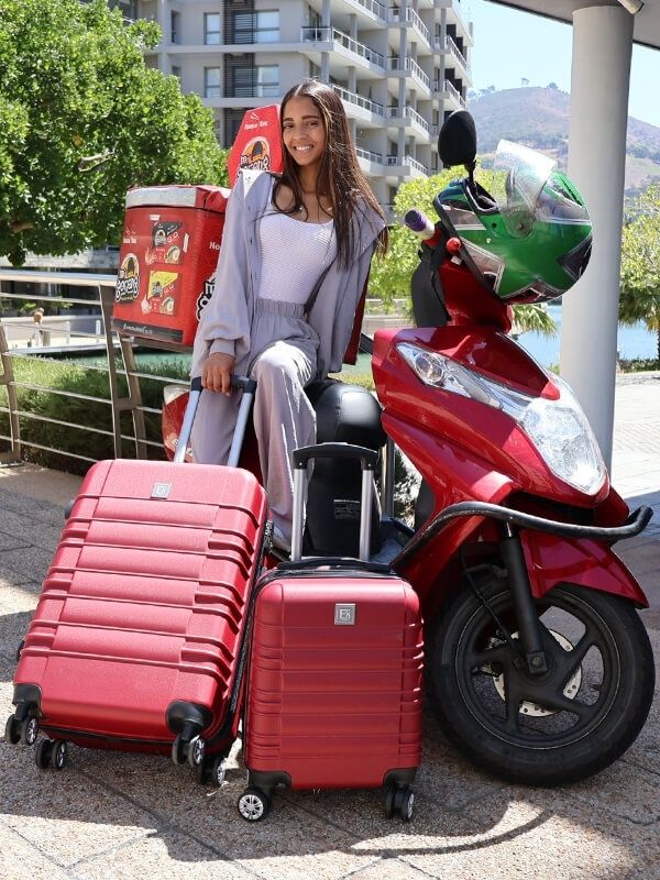 Lifestyle image of the Santorini hardshell luggage set in a tranquil outdoor environment, featuring a couple near the bags, highlighting its soft blue color, modern design, and effortlessly serene travel aesthetic