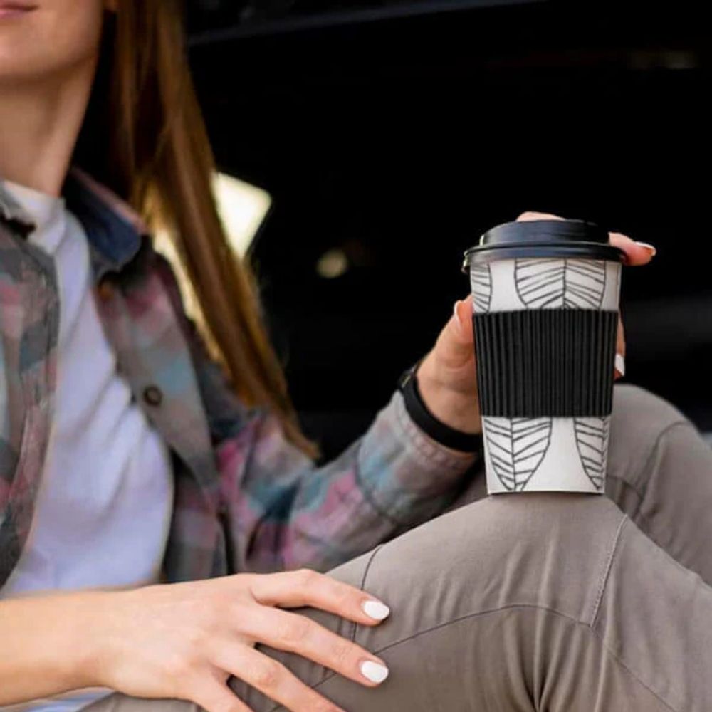 Lifestyle image of a young woman holding the Bamboo Coffee Cup outdoors, showcasing its reusable design and comfortable grip in a casual, eco-conscious moment