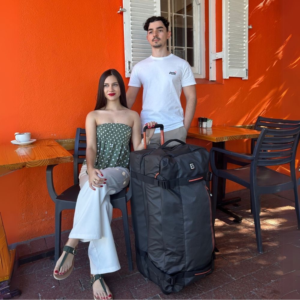 Man and woman with Dallas eco-friendly travel duffel bag seated outside vibrant café – lifestyle product image 01
